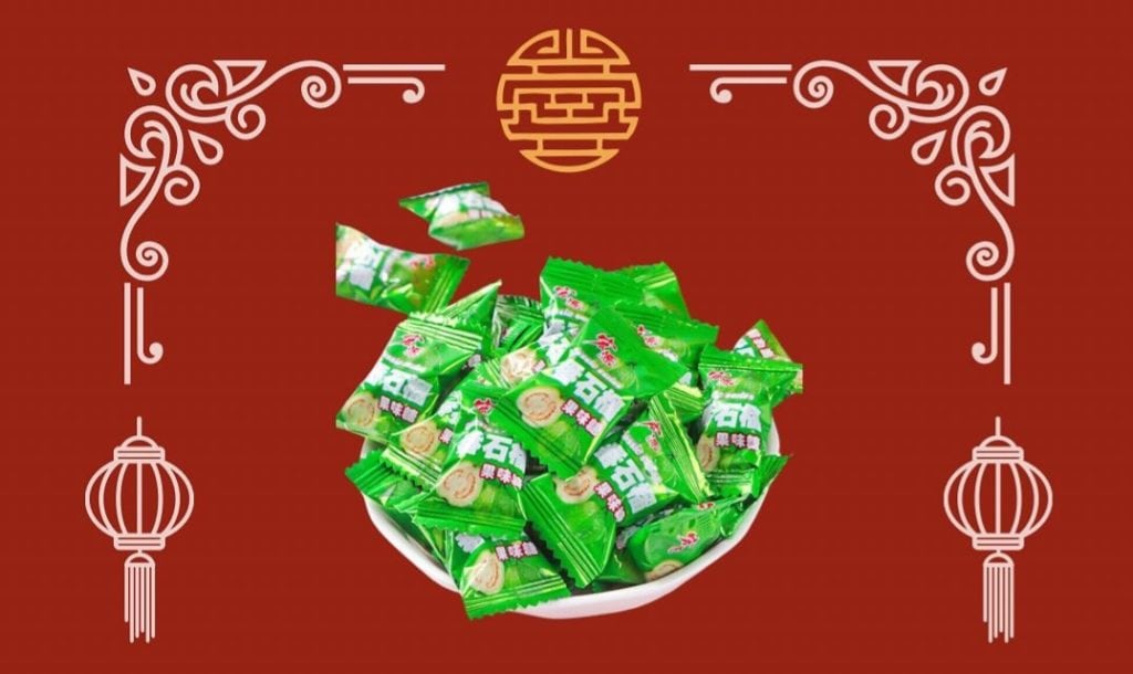 A festive red background adorned with traditional Asian patterns and lanterns frames a white bowl overflowing with wrapped green treats, possibly symbolizing prosperity and celebration for an occasion such as the lunar new year. Discover more