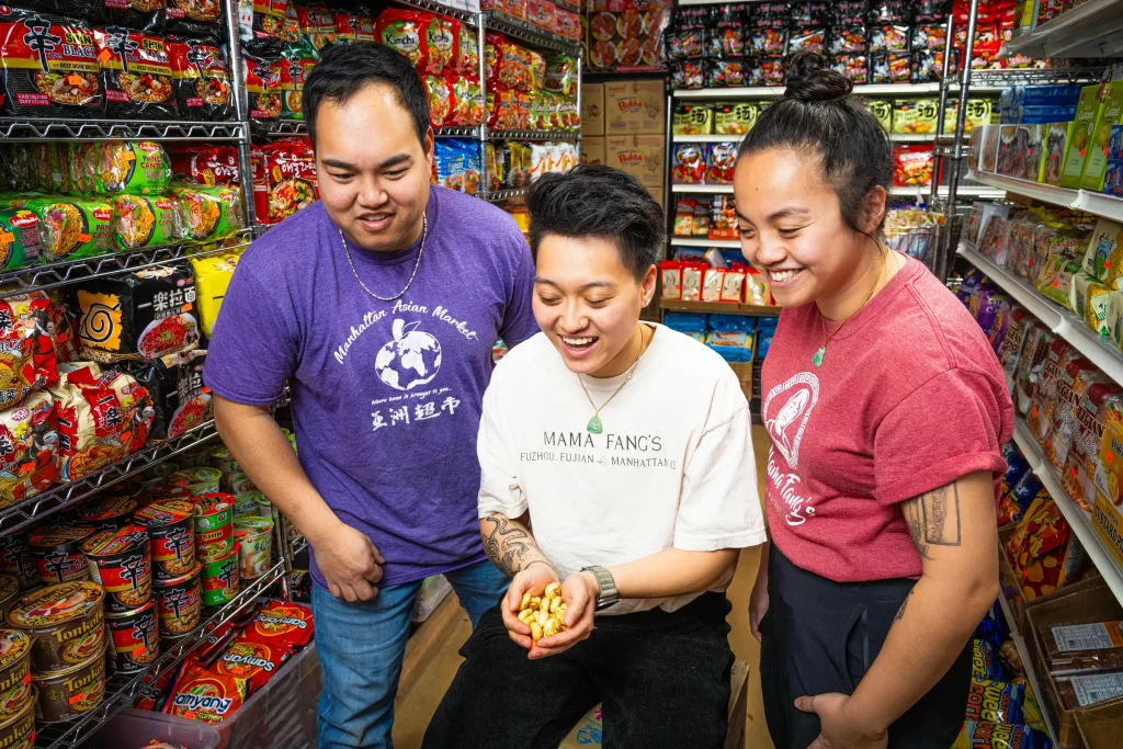 Three friends sharing a light-hearted moment in an asian grocery store, surrounded by a colorful array of snack options.