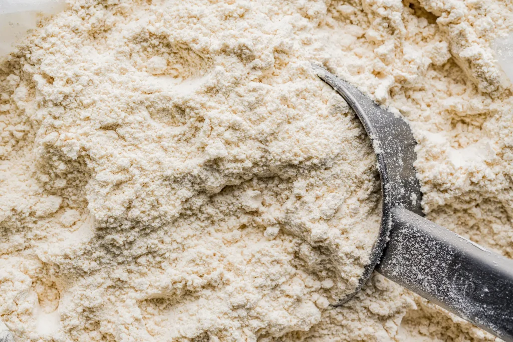 A metal scoop in a container of white flour.