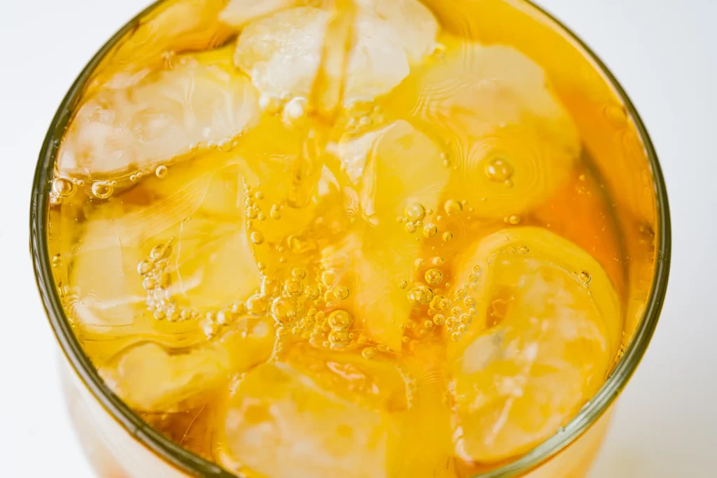 Close-up of a glass of iced orange soda with bubbles.