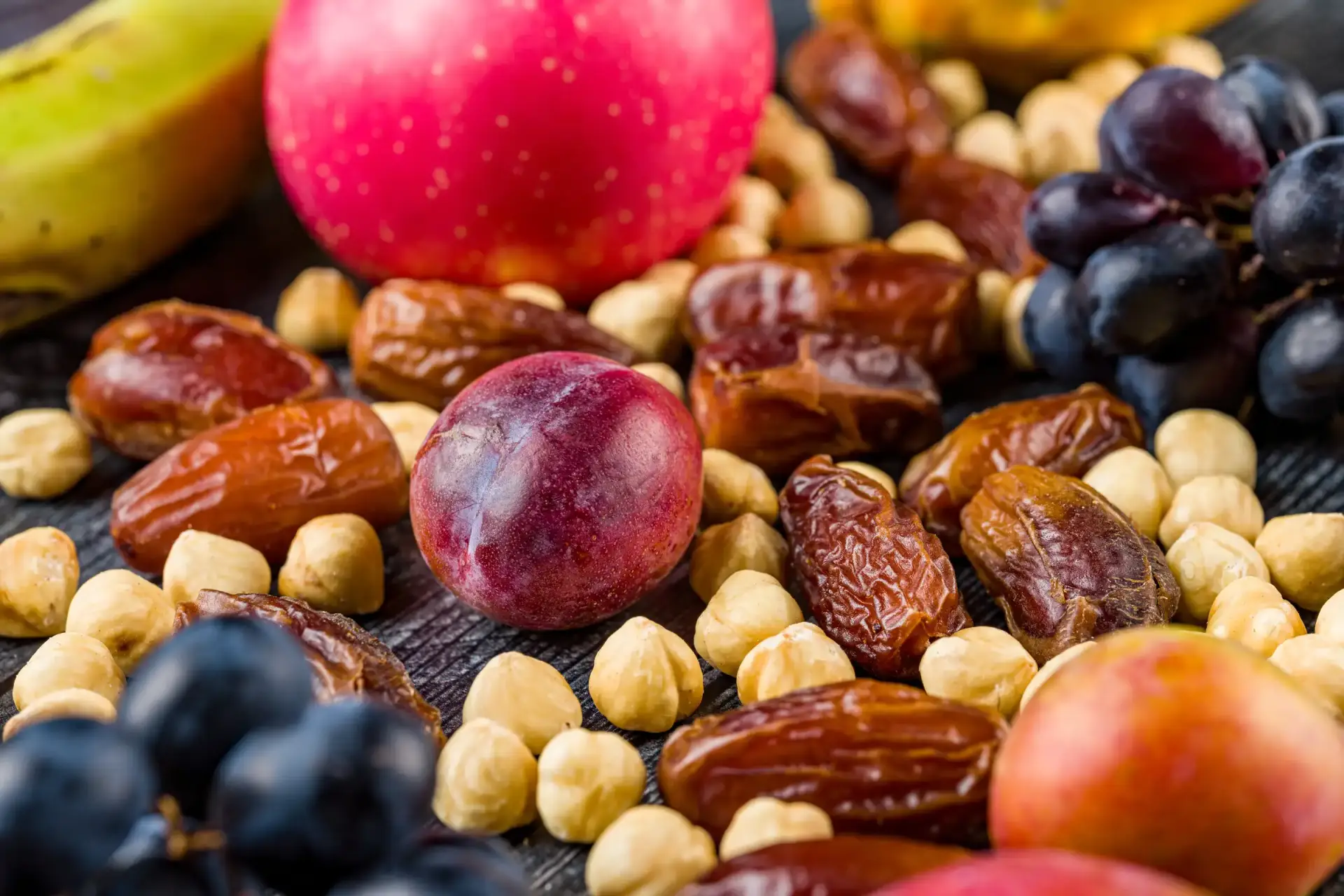 Assortment of fresh and dried fruits with nuts on a wooden surface.